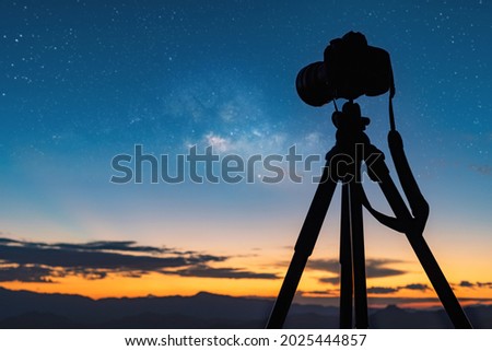 Silhouette of a camera on the tripod at the starry night and bright milky way galaxy.night landscape
