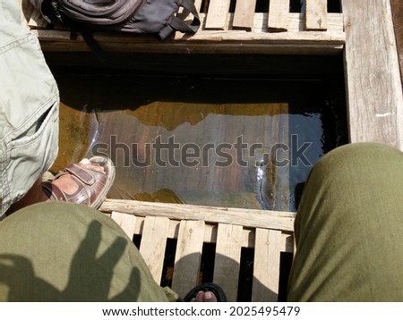Clear water in wooden bilge of boat with people legs and feet Royalty-Free Stock Photo #2025495479