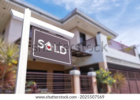 A unique and cute sold sign in front of a 2 gated story house.