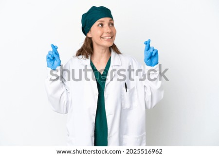 Surgeon caucasian woman in green uniform isolated on white background with fingers crossing