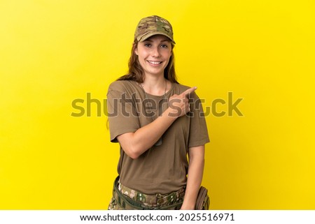 Military caucasian woman with dog tag isolated on yellow background pointing to the side to present a product