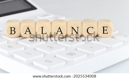Wooden cubes with text BALANCE on the calculator, business concept