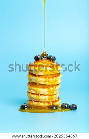 Pancakes with berries on a blue banner background. Lush delicious pancakes with blueberries and syrup for brunch on a minimal colored background. Beautiful bright food photo