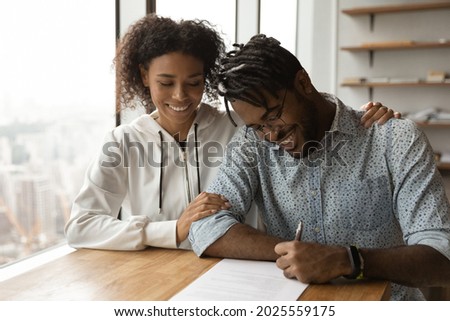 Happy African young family, 35s couple husband and wife sign legal paper insurance contract, millennial clients customers put signature on formal document, make financial deal, take bank loan concept