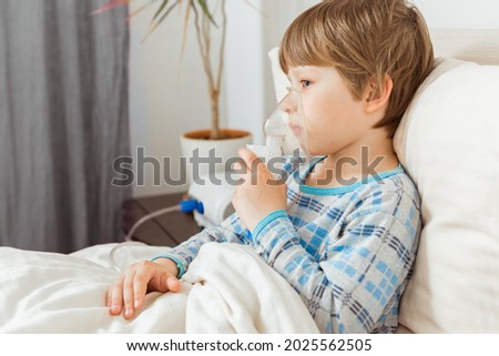 Boy with a respiratory syncytial virus, inhaling medication through an inhalation mask. Flu, coronavirus concept Royalty-Free Stock Photo #2025562505