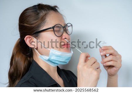 Young Asian woman using rapid antigen test kit by nasal swab herself for takes a sample of cells from the nasopharynx. Rapid antigen testing is a screening tool to help detect COVID-19.