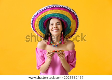 Beautiful young Mexican woman with tasty quesadilla on color background Royalty-Free Stock Photo #2025582437