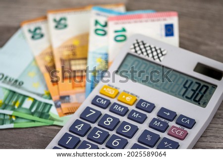 50 100 euro banknotes with calculator on wooden surface
