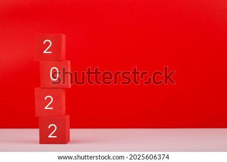 2022 Happy New Year red minimal trendy concept. Modern composition with red toy blocks with written 2022 numbers against red background with copy space. 