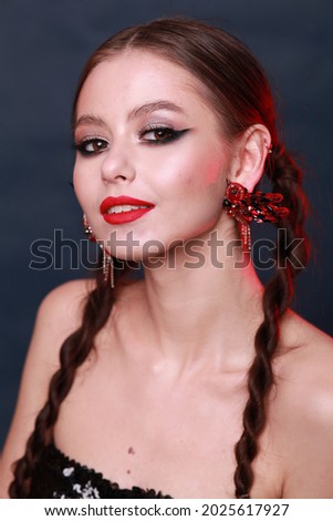 Head shot Portrait of happy brunette  Cheerful girl with perfect clean skin. Beauty face Portrait. Hairstyle with braids. Bright make up with red lipstick. Playful mood. Statement earring bird jewelry