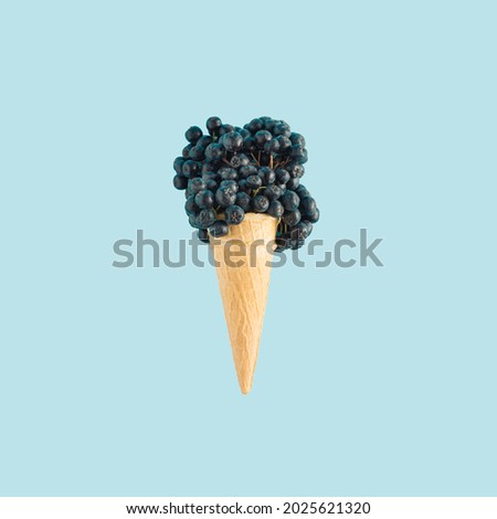 Creative idea of ice cream with berry fruit, chokeberry, in a cone on blue background. Minimal summer or healthy dessert concept. Royalty-Free Stock Photo #2025621320