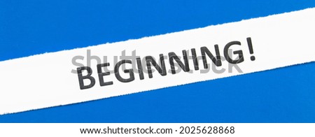 A white strip of paper on a blue background. The inscription "Beginning"