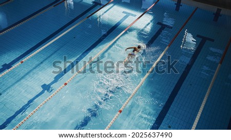 Aerial Top View: Beautiful Female Swimmer in Swimming Pool. Professional Athlete Swims in Freestyle Front Crawl Style. Determined Person in Training to Win Championship. High Angle View Royalty-Free Stock Photo #2025637490
