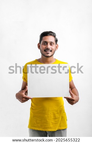 Young Indian man showing blank sing board over white background