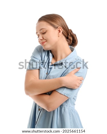 Young woman embracing herself on white background