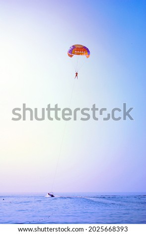 The parachutist flies high in the sky above the blue sea. The concept of recreation at sea