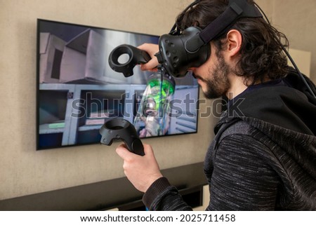 Young male playing games with virtual reality glasses. He immersed himself in the game. Royalty-Free Stock Photo #2025711458