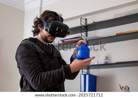 Young male holding a conference call with virtual reality glasses. The young engineer talks about his work. Royalty-Free Stock Photo #2025721712