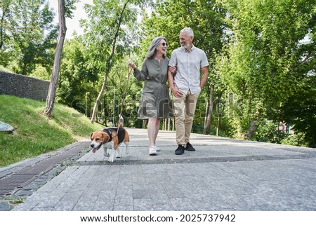 Couple of pensioner enjoying summer walking while going through the park Royalty-Free Stock Photo #2025737942