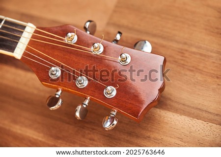 Guitar headstock on a wooden surface. Close-up horizontal image. Royalty-Free Stock Photo #2025763646
