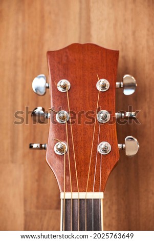 Front view of a guitar headstock. Close-up vertical image with wood background. Royalty-Free Stock Photo #2025763649