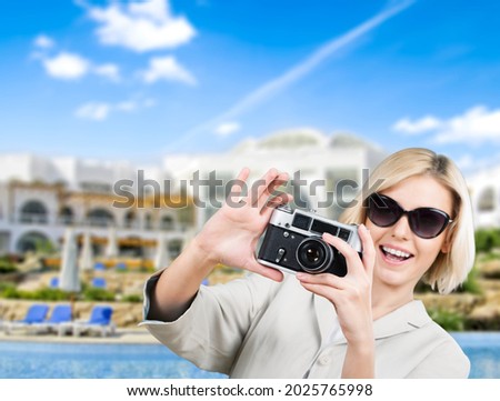 Photography and travel. Young woman taking a photo with her camera on the beach