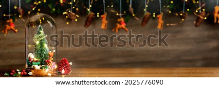 Merry Christmas and Happy new year xmas tree and santa claus in glass dome decor with bauble reindeer,pine cone tinsel at wood background.Table Banner space for display product