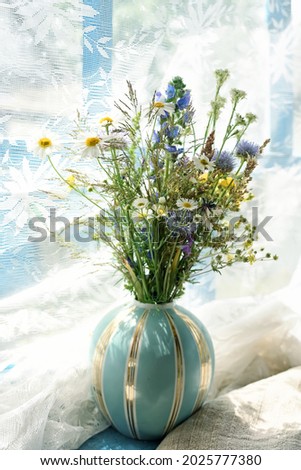 A cute bouquet of wildflowers in a vase on the veranda window. gentle rays of sunlight. Vintage retro style photo
