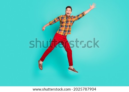 Full length photo of cool brunet millennial guy jump wear shirt trousers sneakers isolated on teal background