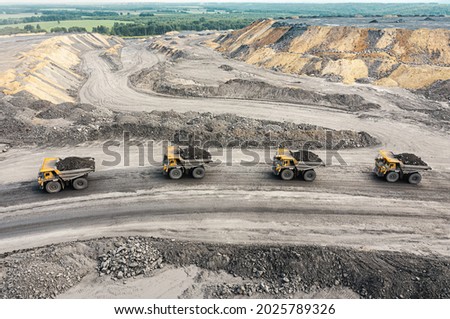 Large quarry dump truck. Big yellow mining truck at work site. Loading coal into body truck. Production useful minerals. Mining truck mining machinery to transport coal from open-pit production Royalty-Free Stock Photo #2025789326