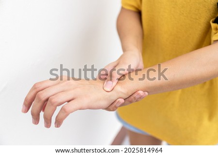 Woman in yellow clothes using hand to hold wrist with feeling pain, suffer, hurt and tingling. Concept of Guillain barre syndrome and numb hands disease.