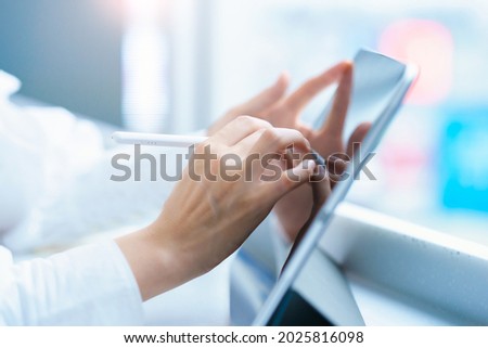 Female hand operating a tablet PC with a stylus pen