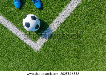 Soccer football background. Soccer ball and pair of football sports shoes on artificial turf soccer field with white line. Top view Royalty-Free Stock Photo #2025816362