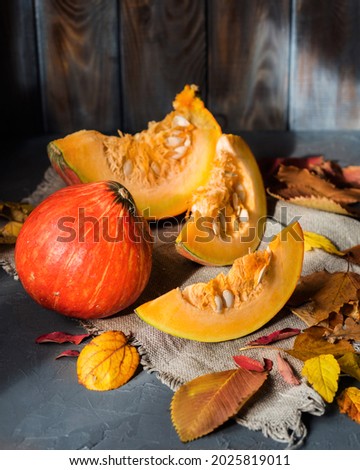 Autumn still life. Pumpkins and yellow leaves. Chopped pieces of pumpkin. Autumn background. Chiaroscuro in food photography