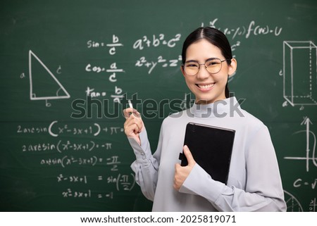 Young asian teacher woman teaching holding book and chalk video conference with student looking camera. Female teacher training the mathematics in classroom blackboard from online course. Royalty-Free Stock Photo #2025819071