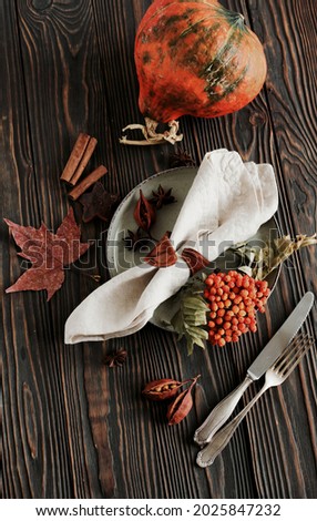 Autumn Thanksgiving dinner table setting with pumpkins, fallen leaves and vintage cutlery top view. Copy space.Toned. Rustic autumn traditional seasonal table setting at home.