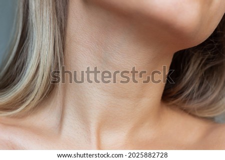 A close-up view of a young woman's neck and collarbone . Lines on the neck. Wrinkles, age-related changes, rings of Venus, goosebumps. Skin care. Close-up Royalty-Free Stock Photo #2025882728