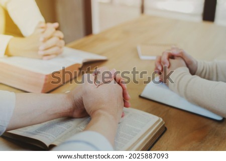 Christian small group  praying on  blurred open bible page on a wooden table while studying the bible together in homeroom, devotional or prayer meeting concept Royalty-Free Stock Photo #2025887093