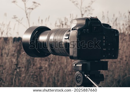 A camera on a tripod takes pictures of the hills at sunset, the rays of which fall beautifully on the camera.