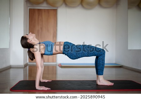 Athletic woman performs reverse plank exercise in gym