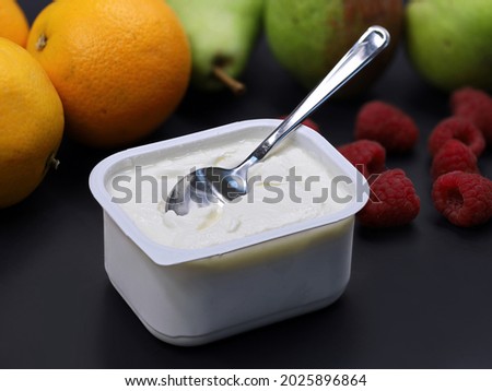 quark or cream cheese in plastic box with spoon on black backround with fruits, healthy nutrition for breakfast Royalty-Free Stock Photo #2025896864