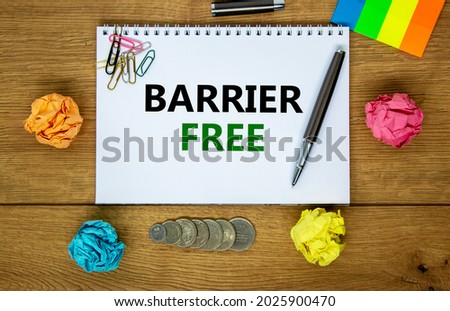 Barrier free symbol. Words 'Barrier free' on white note. Wooden table, colored paper, paper clips, pen, coins. Business, diversity, inclusion, belonging and barrier free concept. Copy space.