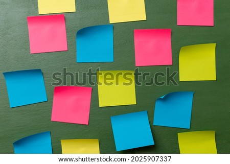 Many blank colorful memory stickers on a dark green background. The empty space on multi-colored office stickers. Busy day, business concept.
