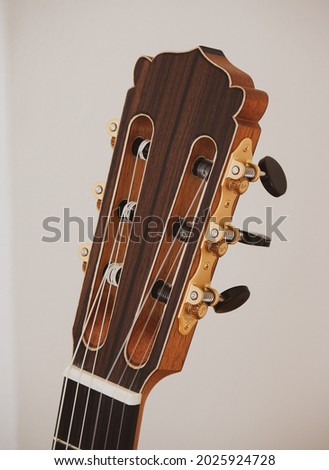 Headstock of a classical acoustic guitar with golden tuning mechanics and black buttons. Royalty-Free Stock Photo #2025924728