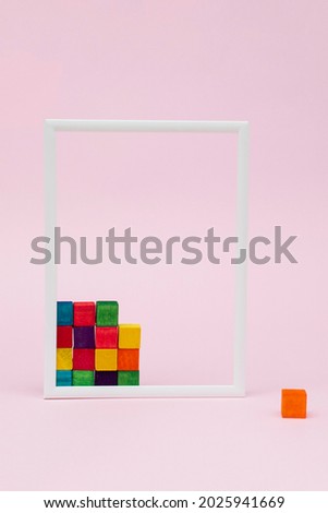 White frame with colorful cubes isolated on pink background.