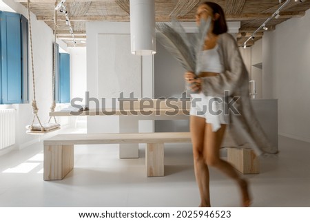 Modern studio apartment interior with motion blurred female person walking, decorating home. Home coziness, self-isolation and comfort at home concept
