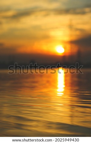 Beautiful sunset near the water, the water is in focus and the background is blurred, vertically