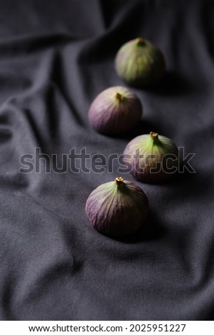 Autumn still life. Figs on a dark background. Fruit harvest. Four figs on a black napkin. Dark food photography. Food in the style of minimalism. Vegan