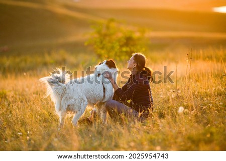 woman with dog playing in autumn landscape