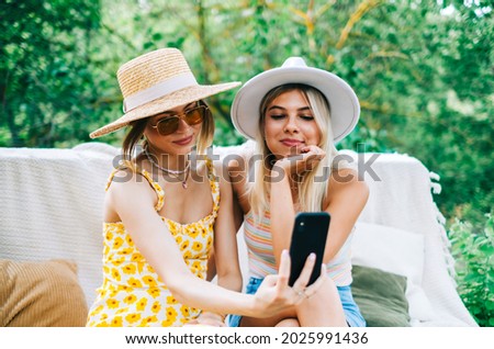 Two young cheerful women having fun and making photo outdoor in the garden.
